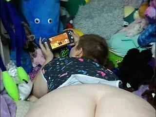 Una ragazza amatoriale pallida si diverte a giocare ai videogiochi mentre lei la mangia