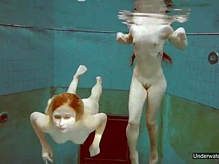 Kaksi upeaa tyttöä uima-altaassa ja leikkivät vartaloillaan